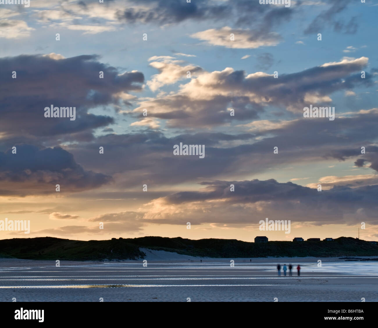 Quattro persone che camminano sulla spiaggia di Embleton verso il villaggio di Newton sulla costa Northumbrian, Northumberland, Inghilterra Foto Stock