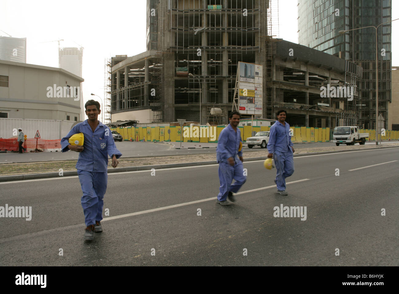 I lavoratori migranti nel settore delle costruzioni a Doha, in Qatar, attraversando la strada. Foto Stock