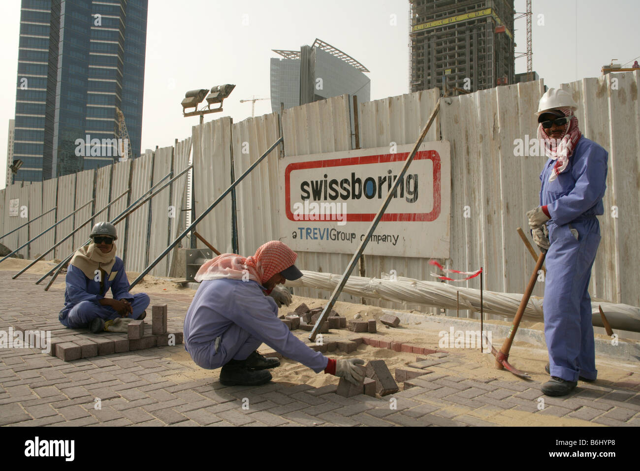 I lavoratori migranti posando mattoni per pavimentazione a Doha, in Qatar. Foto Stock