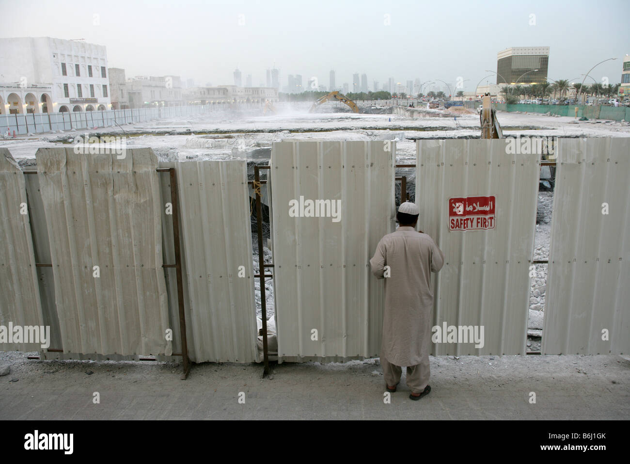 L uomo del peering attraverso la demolizione di recinzione del sito con sicurezza rosso primo segno, Doha, Qatar, Medio Oriente Foto Stock
