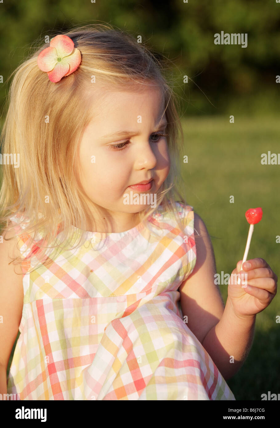 Bambina di mangiare una ventosa e cercando in questione Foto Stock