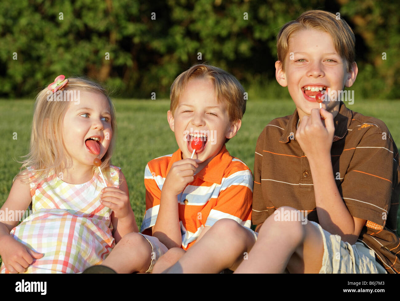 Tre bambini sorridenti e ventose per mangiare all'aperto Foto Stock
