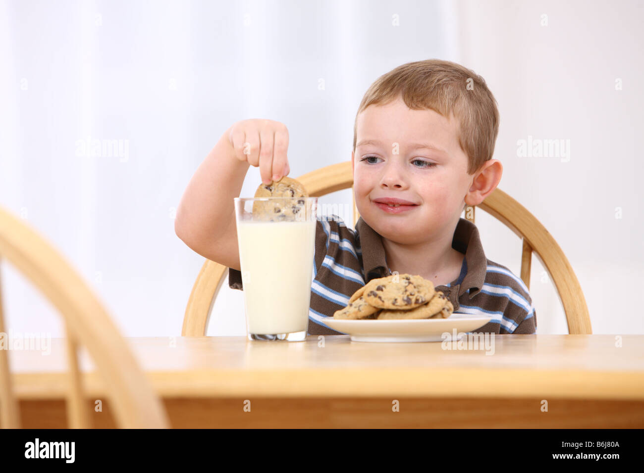 Giovane ragazzo cookie di immersione nel bicchiere di latte Foto Stock