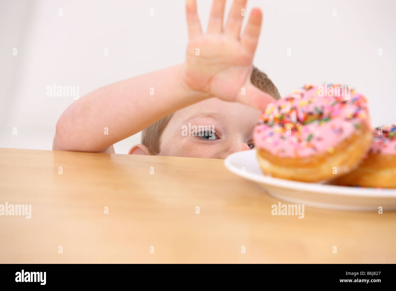 Giovane ragazzo per raggiungere le ciambelle su tavola Foto Stock