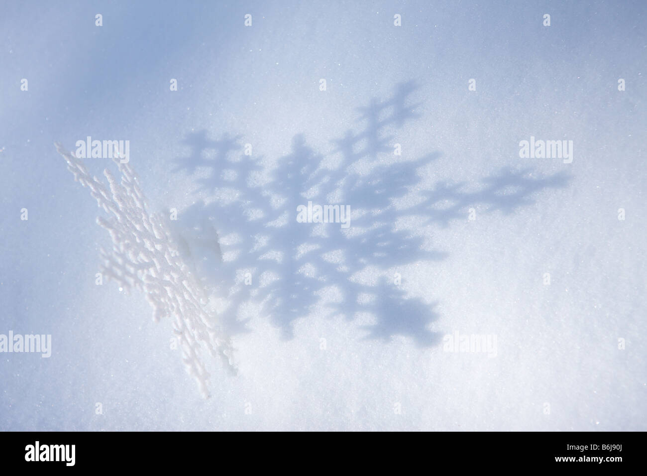 Il simbolo del fiocco di neve invernale getta un' ombra sulla neve Foto Stock