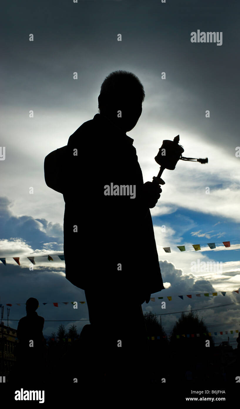 Silhouette di un pellegrino tibetano la filatura di una prayerwheel come egli fa un perumbulation del monastero di Jokhang, Lhasa, in Tibet Foto Stock