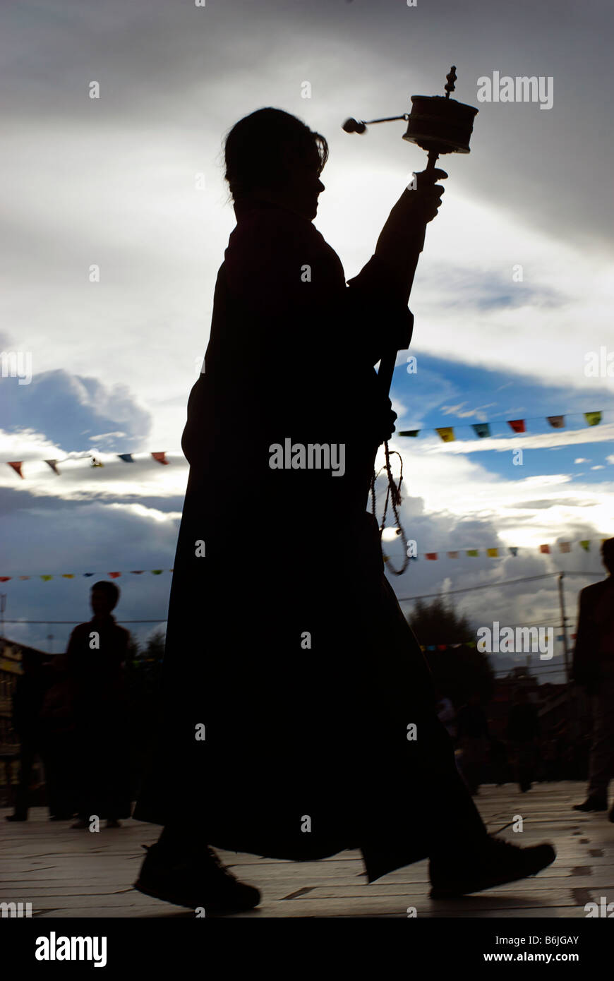 Silhouette di un pellegrino tibetano la filatura di una prayerwheel come lei fa un perumbulation del monastero di Jokhang, Lhasa, in Tibet Foto Stock