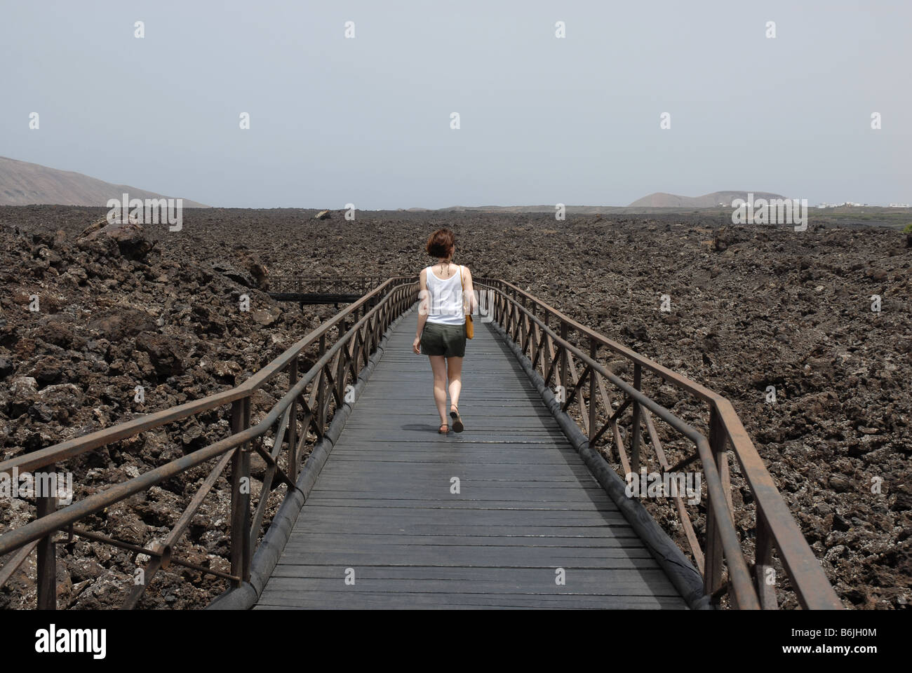 Un turista passeggiate su campi di lava presso il centro visitatori del Parco naturale de los volcanes e Parque Nacional de Tim Foto Stock