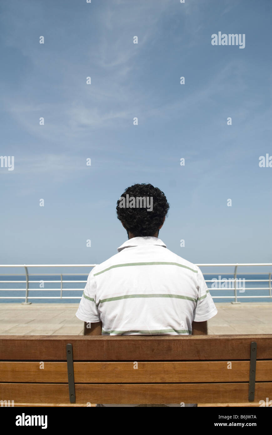 Uomo seduto su un banco in riva al mare Foto Stock