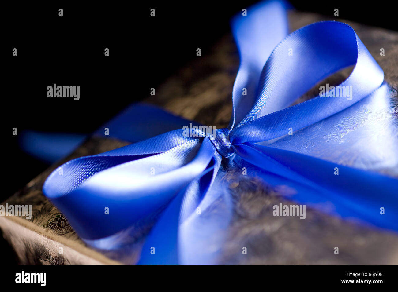 Blue Ribbon legato in un arco sulla argento regalo alta risoluzione Immagine ripresa con obiettivo Macro macchiato con cautela e ritoccate Foto Stock