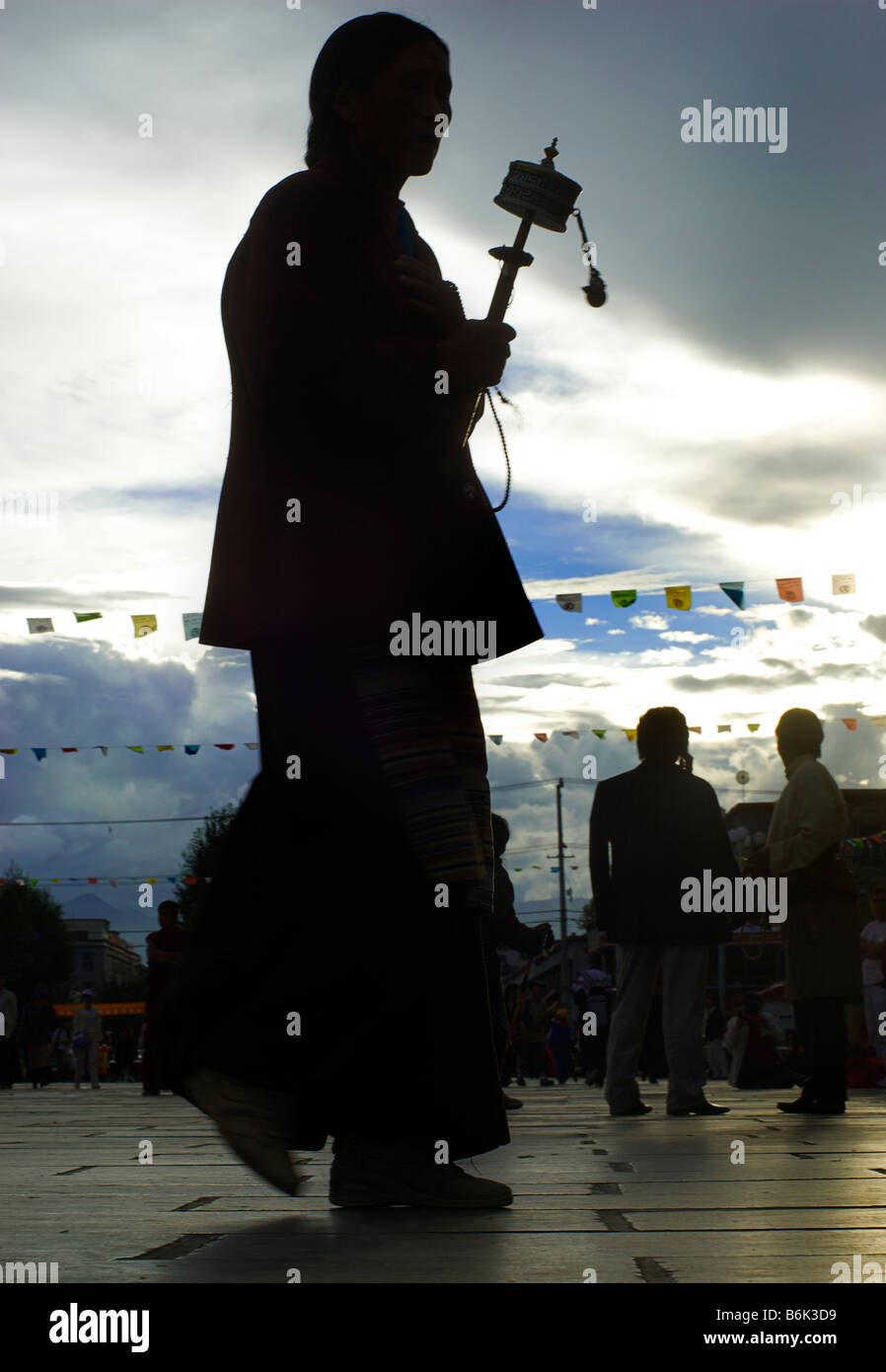Silhouette di un pellegrino tibetano la filatura di una prayerwheel come egli fa un perumbulation del Jokhang, Barkhor Square, Lhasa, in Tibet Foto Stock