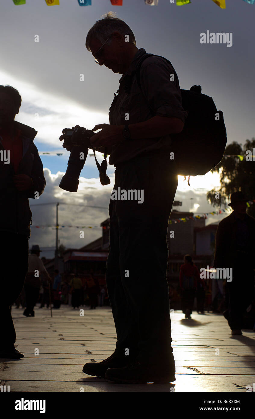 Silhouette di un fotografo con una telecamera professionale la revisione di una fotografia. Barkor Square, Tibet Foto Stock