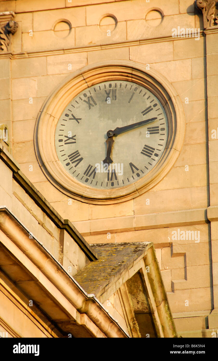 Arancione bagliore del sole che tramonta sulla faccia di orologio che mostra il tempo di 6.12 su numeri romani orologio della torre dell'orologio del palazzo comunale Foto Stock
