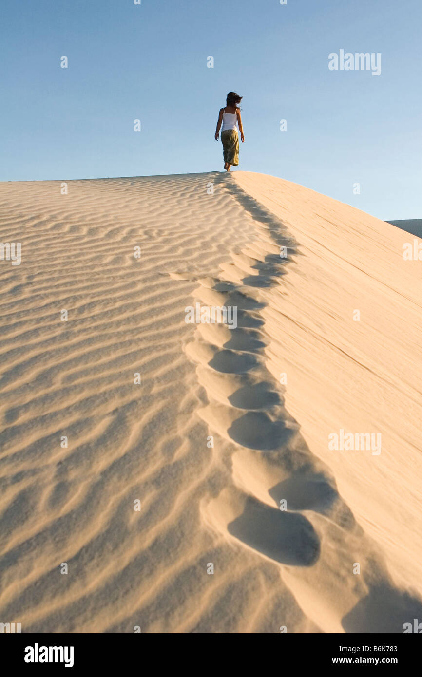 Donna climbing duna di sabbia, Cumbuco, Brasil. Foto Stock