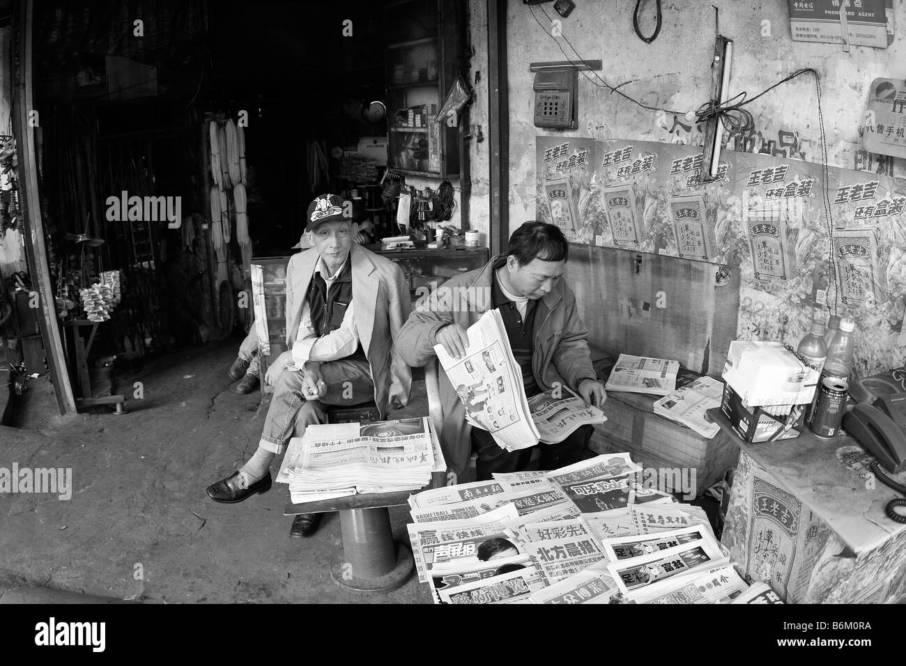 Cinese locale news stand con il Cinese più recente in primo piano due uomini anziani sono in vendita la nuova Cina recentemente tightned restrizioni Foto Stock