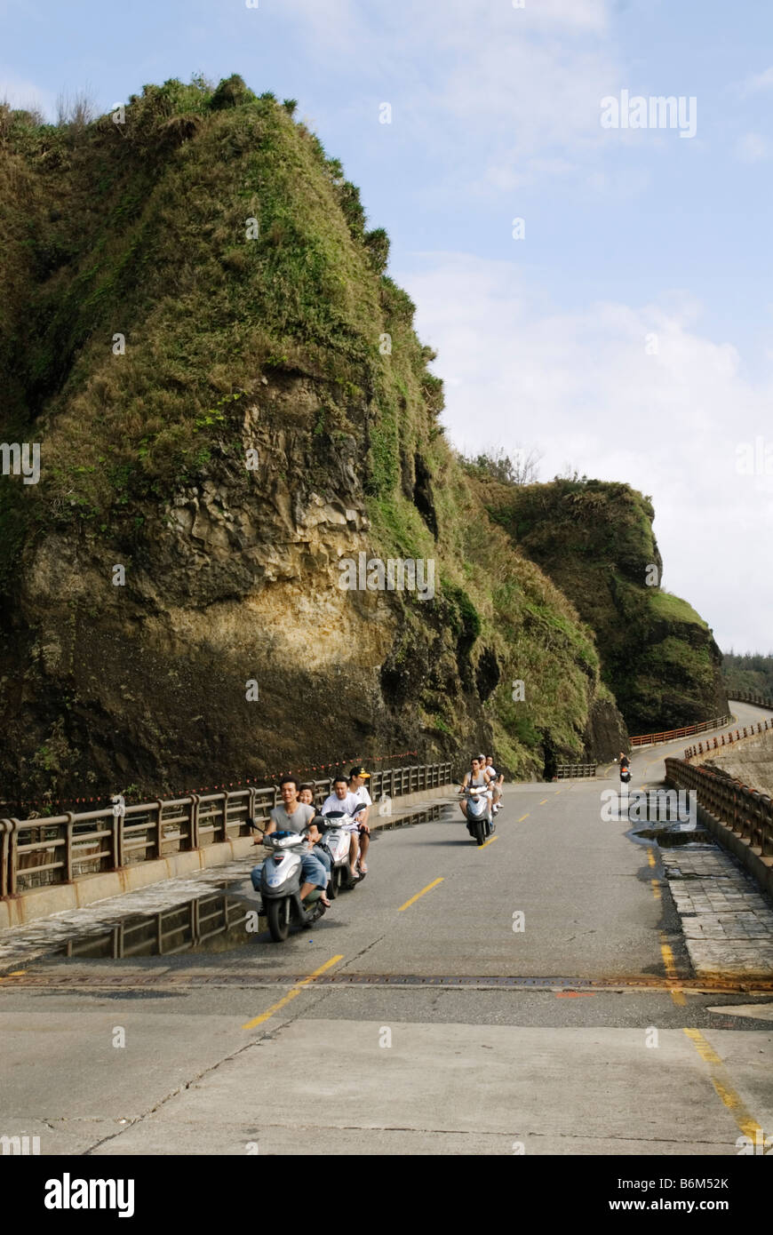 Taiwan, Isola Verde, persone guida scooter lungo su una strada costiera Foto Stock