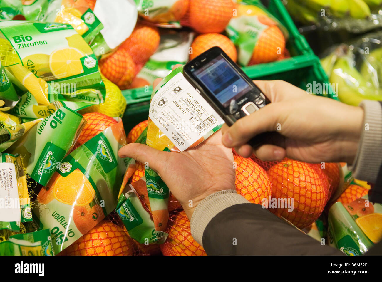 Giovane donna scansiona il prezzo di pacchetti di frutta nel suo telefono cellulare in un supermercato Foto Stock