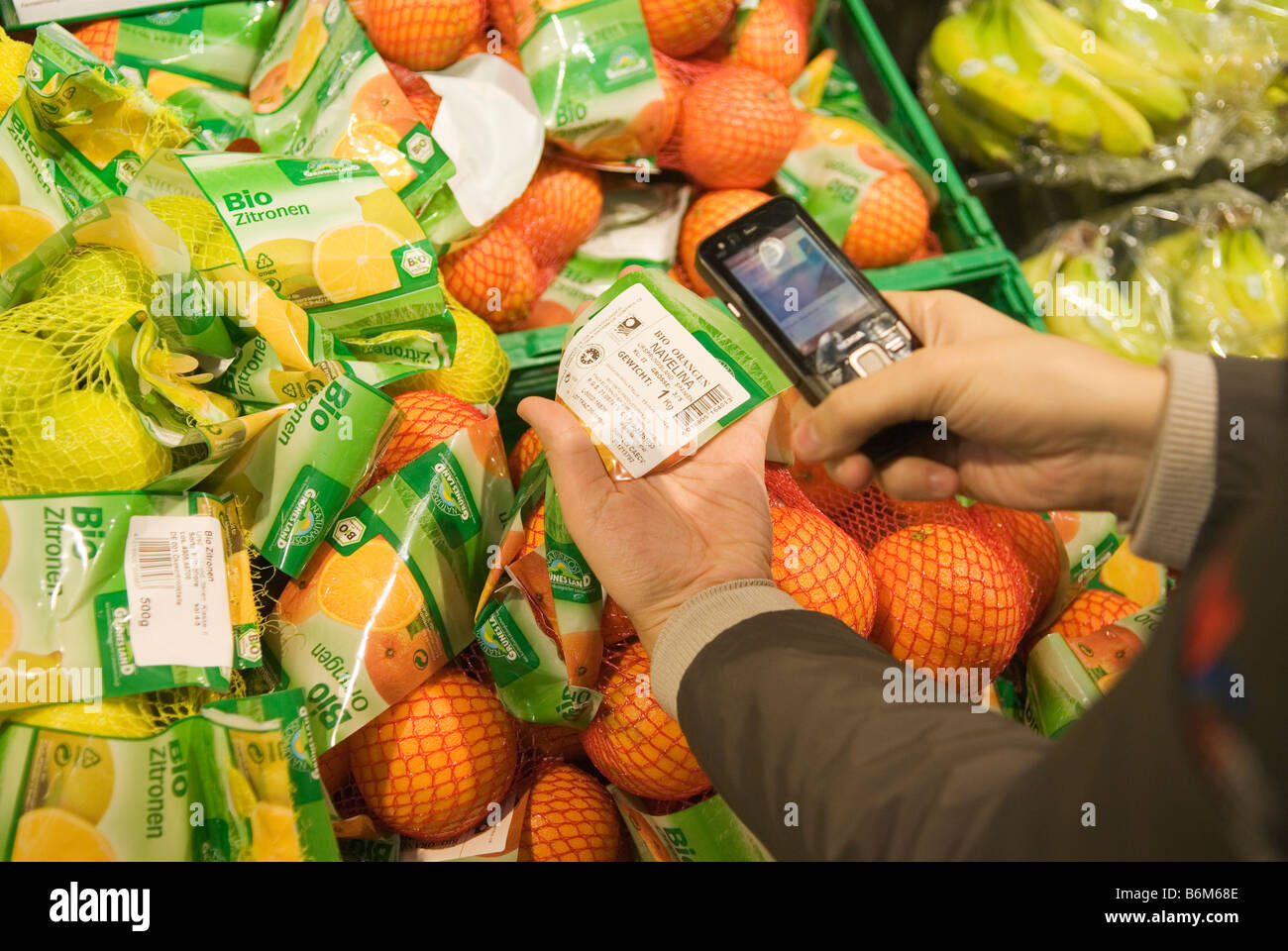 Giovane donna scansiona il prezzo di pacchetti di frutta nel suo telefono cellulare nel futuro reale di memorizzare una parte di Metro Group Foto Stock