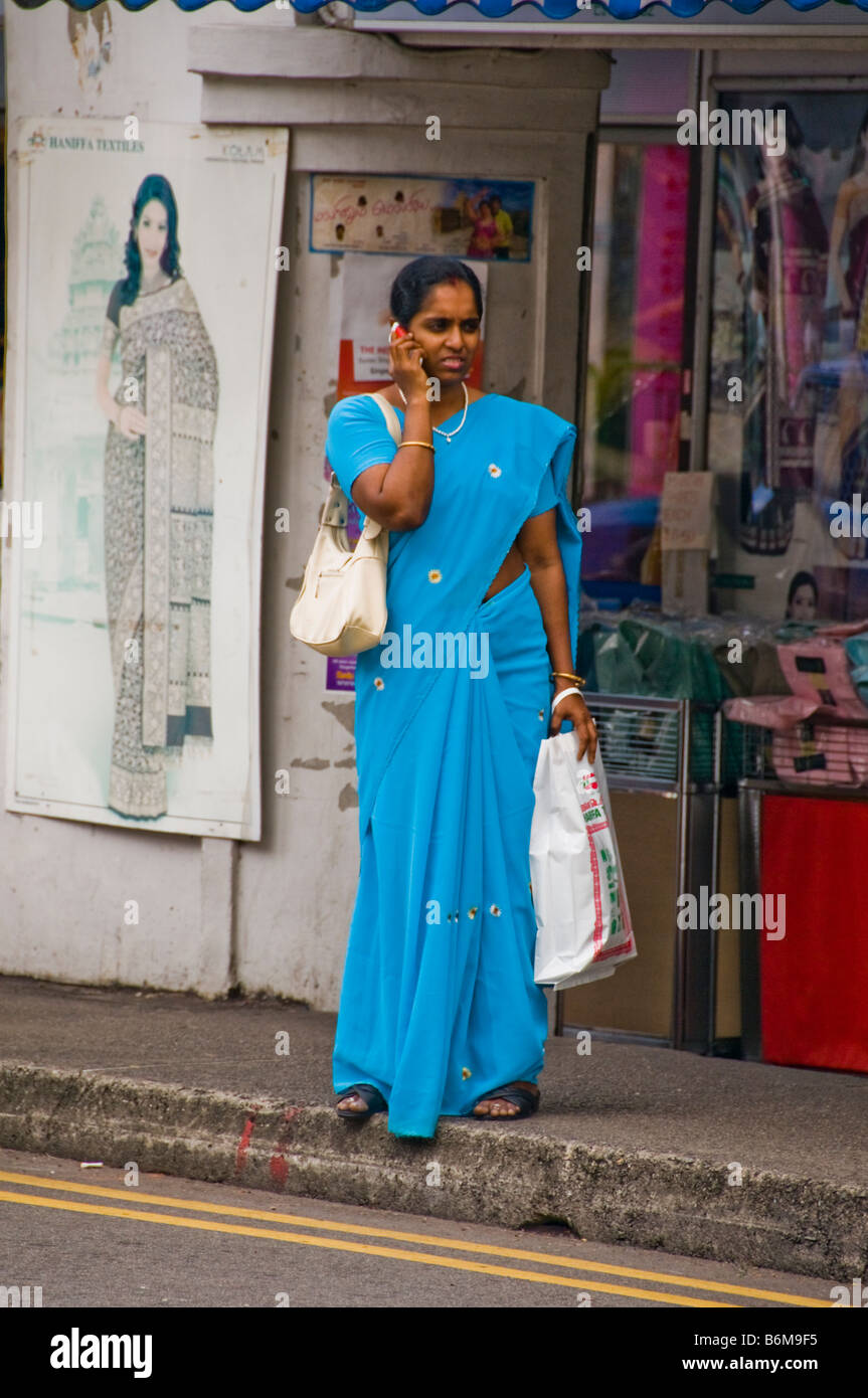 Donna in piedi sulla strada di Little India di Singapore in attesa per autobus Foto Stock