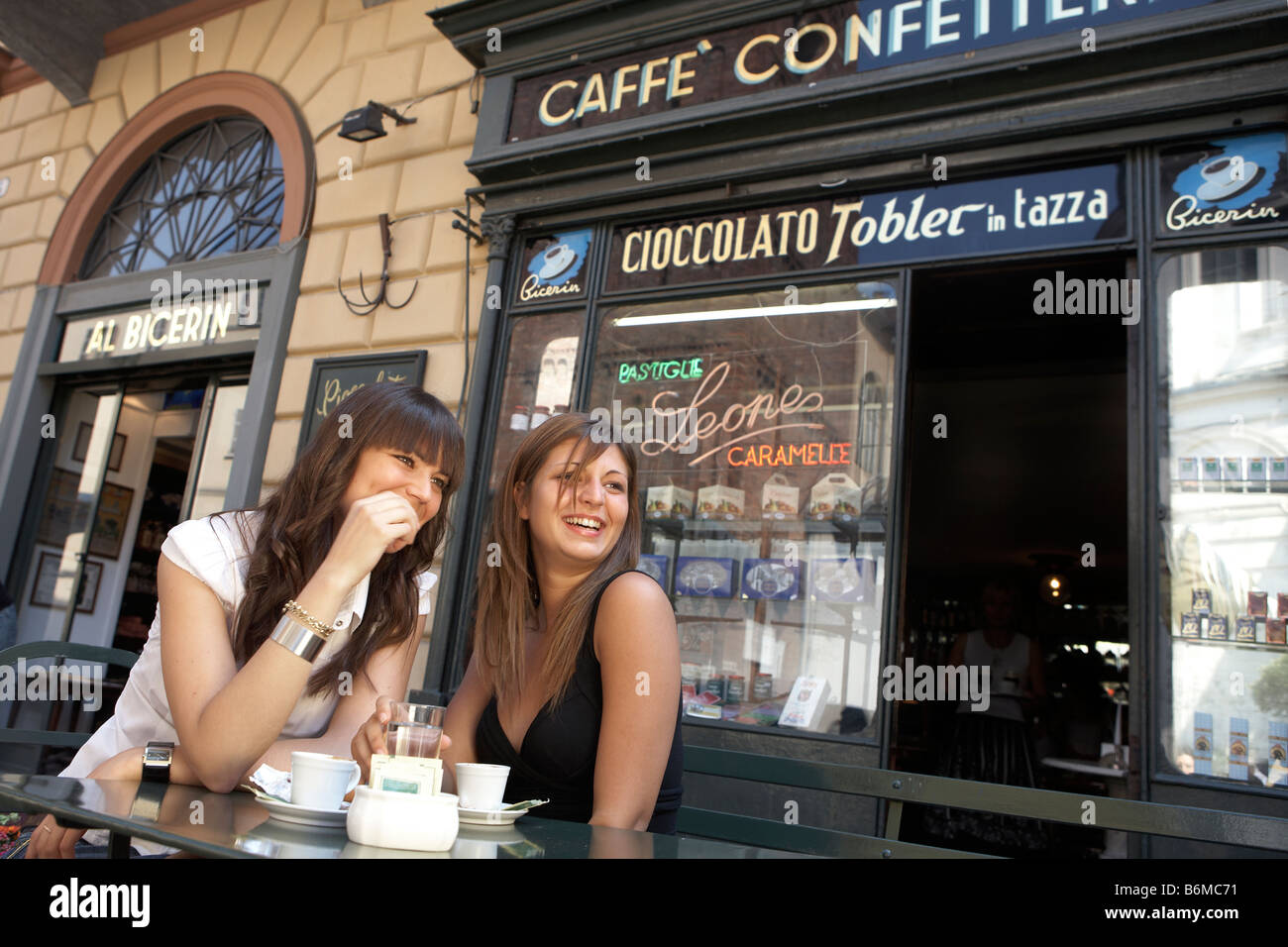 Giovani e belle donne italiane di bere caffè di fronte tipica caffetteria italiana Foto Stock