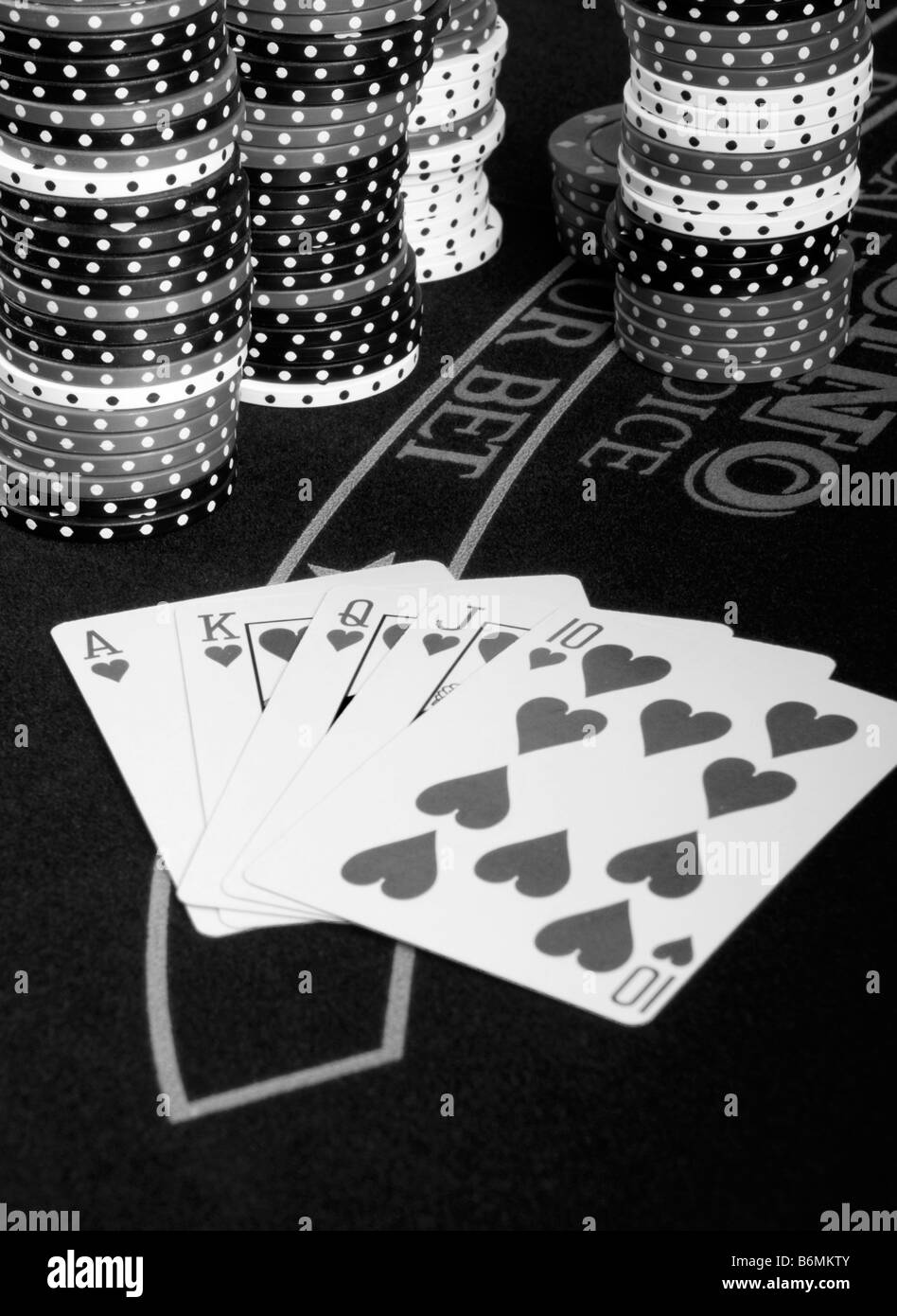 Una vittoria in mano di poker su un tavolo di gioco con poker chips in background - B/W in bianco e nero Foto Stock