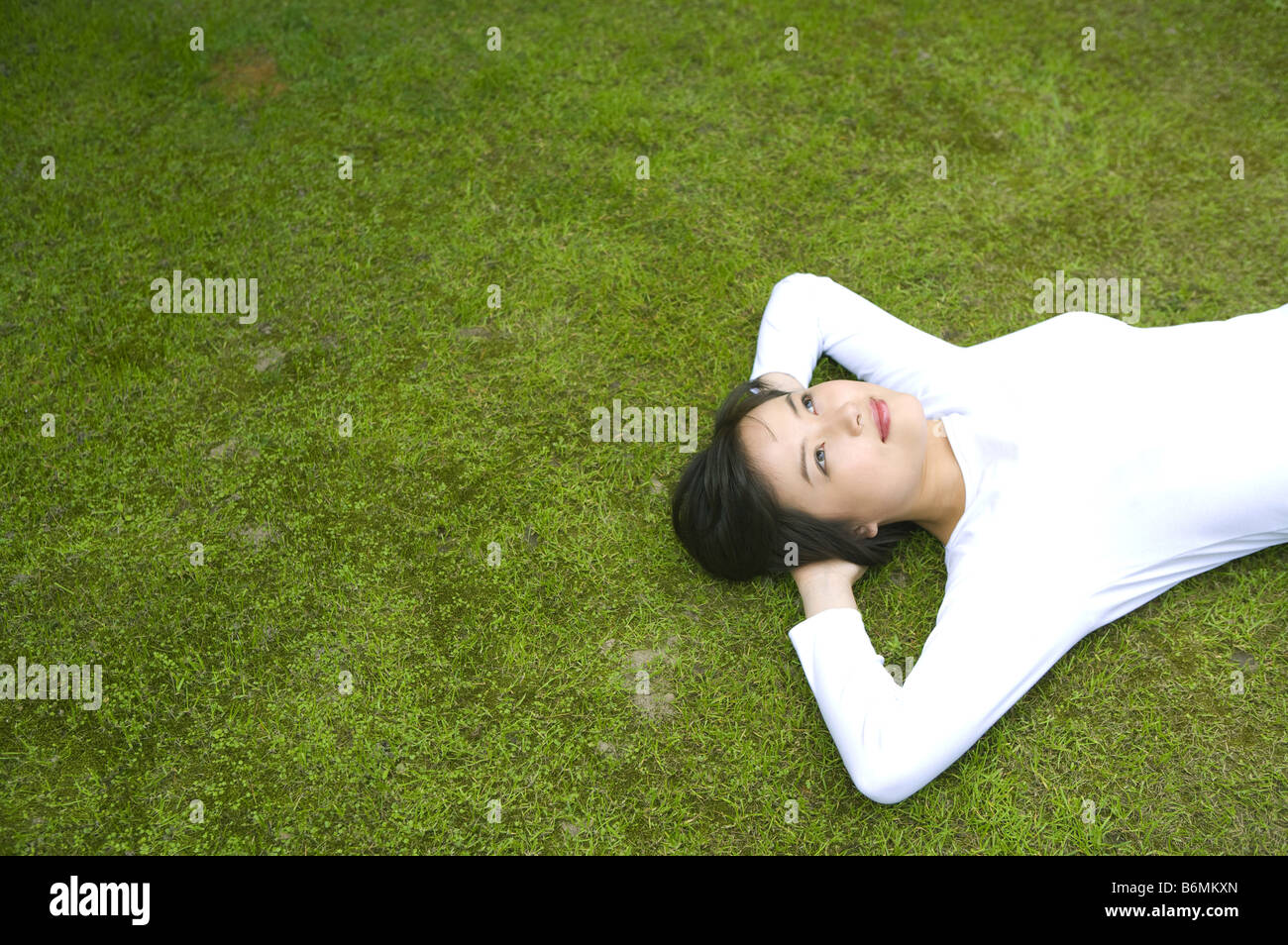 Giovane donna sdraiata su un prato Foto Stock