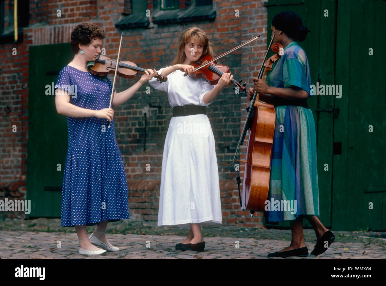 Schleswig Holstein Music Festival, tre giovani donne da Youth Orchestra che suona il violino e violoncello in agriturismo cantiere in Schoenau Foto Stock