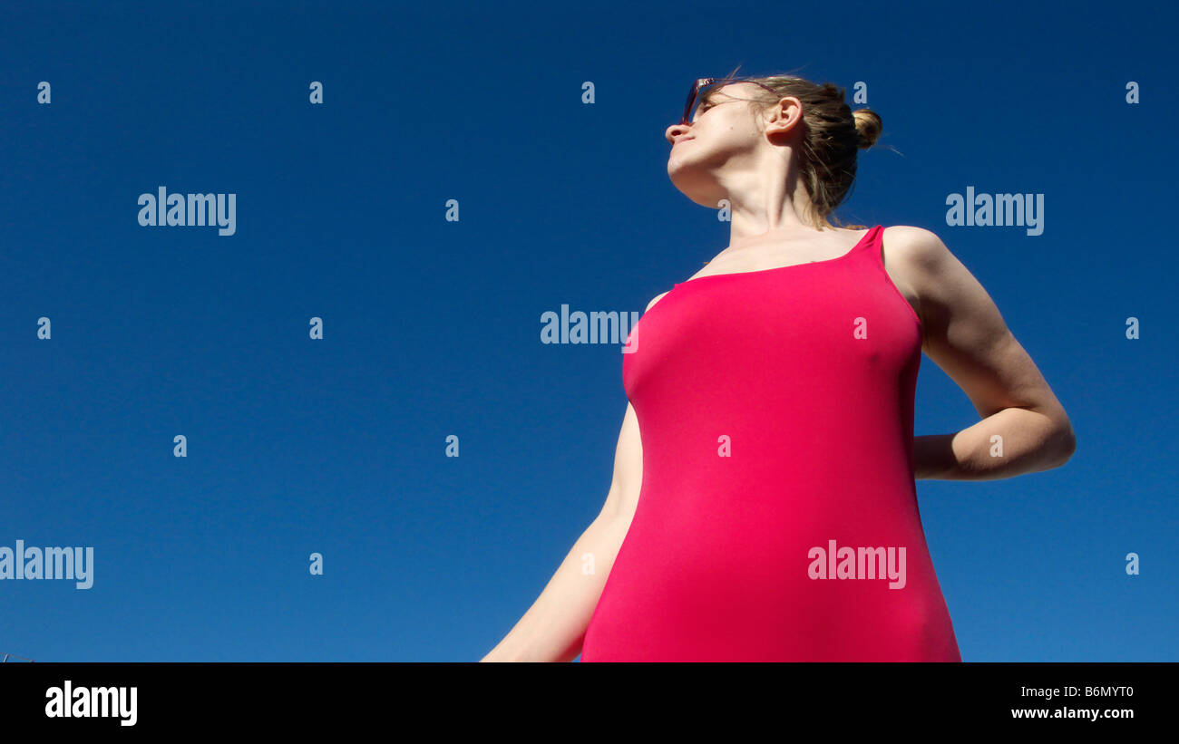 Donna con gli occhiali e bikini rosso contro un cielo blu Foto Stock