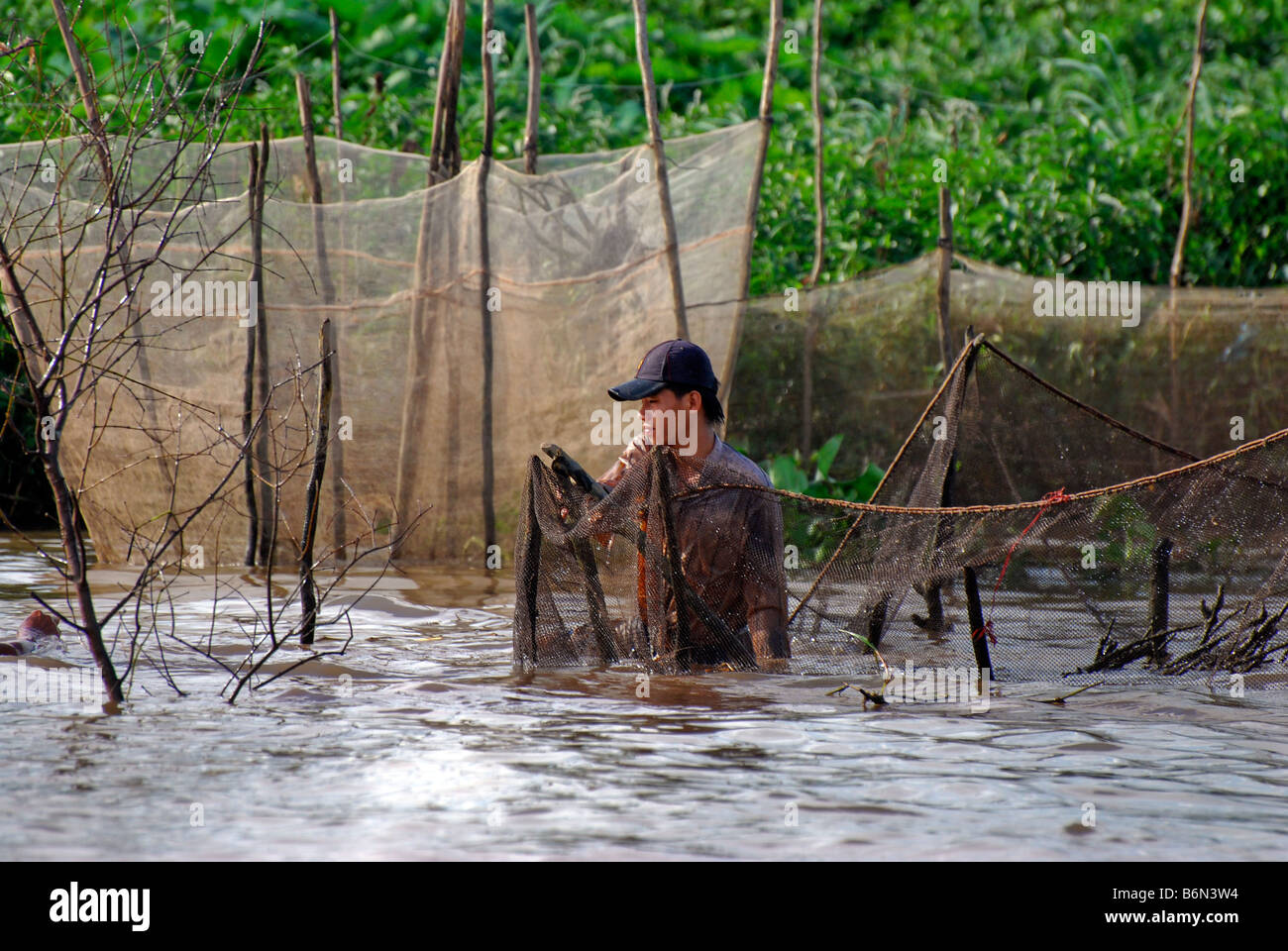 Pescatore con le reti e le banche di Tien Giang River Delta del Mekong, Vietnam Foto Stock