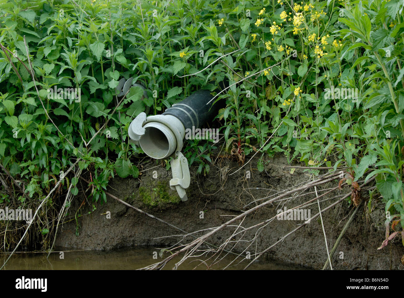 Tubo di irrigazione e di accoppiamento sporgente da un coltivatore campo accanto al Fiume Tamigi vicino a Shepperton, Inghilterra Foto Stock