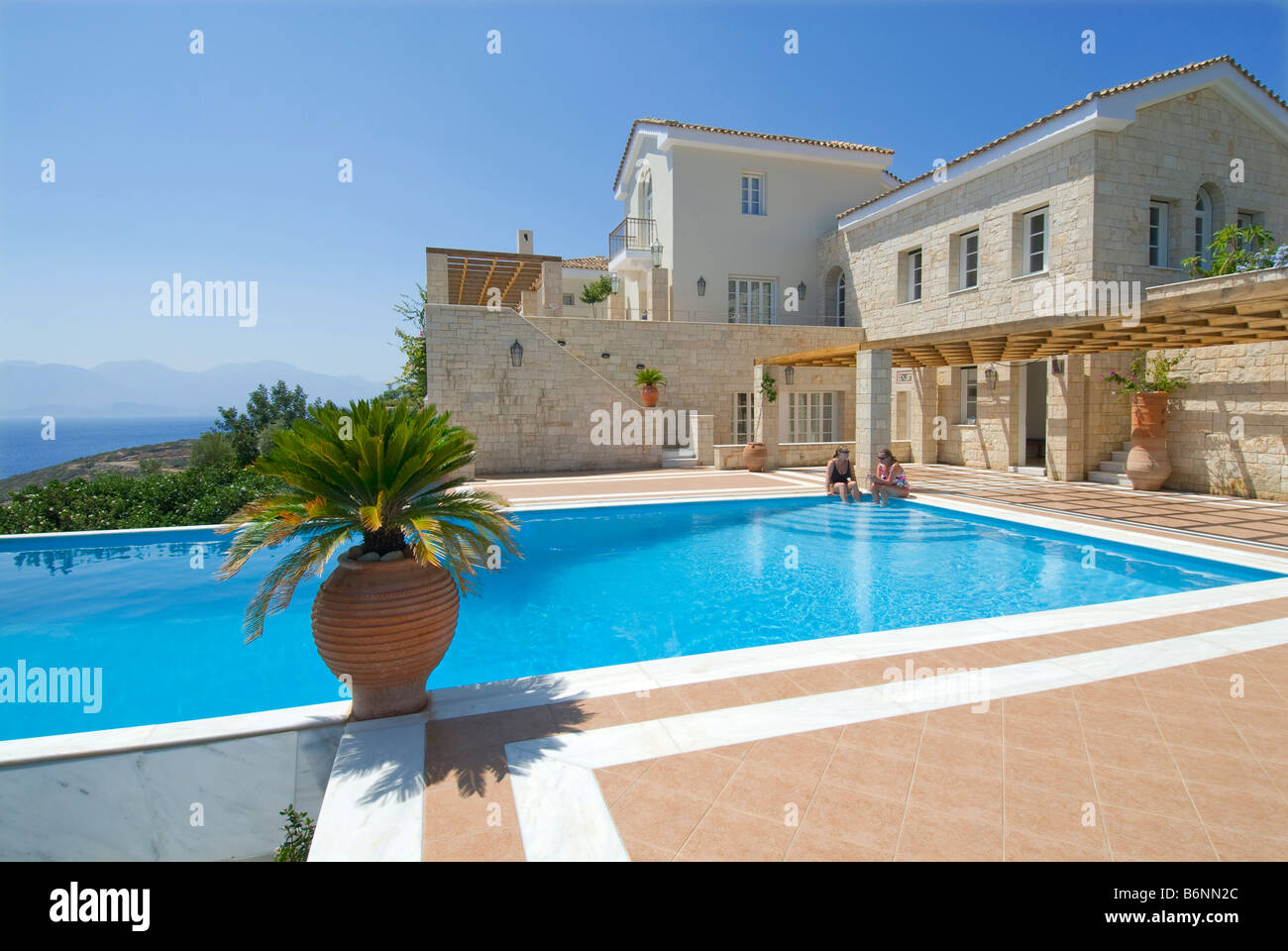 Villa vacanza di lusso ed esclusiva piscina privata a sfioro soleggiata Con vista su Creta e sul mare Egeo, con palme e tipici greci urne Foto Stock