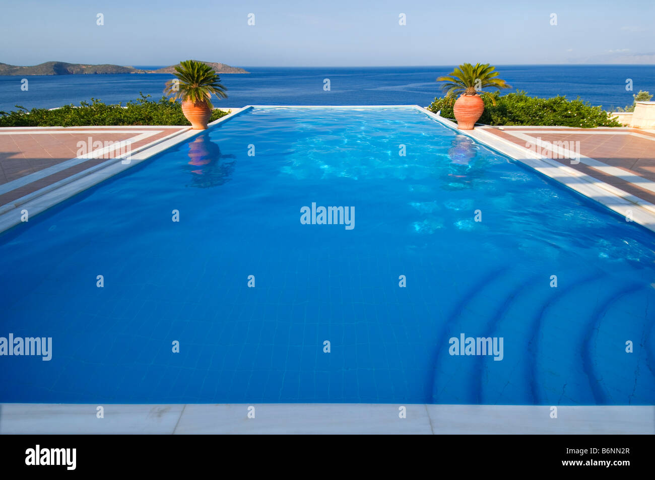 PISCINA INFINITY esclusiva piscina Infinity privata con vista su Creta e sul Mar Egeo, con palme e tipiche urne greciane Foto Stock
