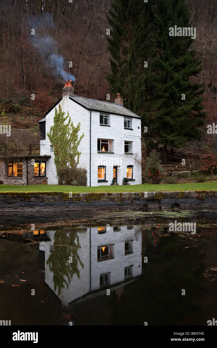 Casa Bianca con fumo dalla ciminiera riflessa nel canal Llanfoist Wales UK Foto Stock