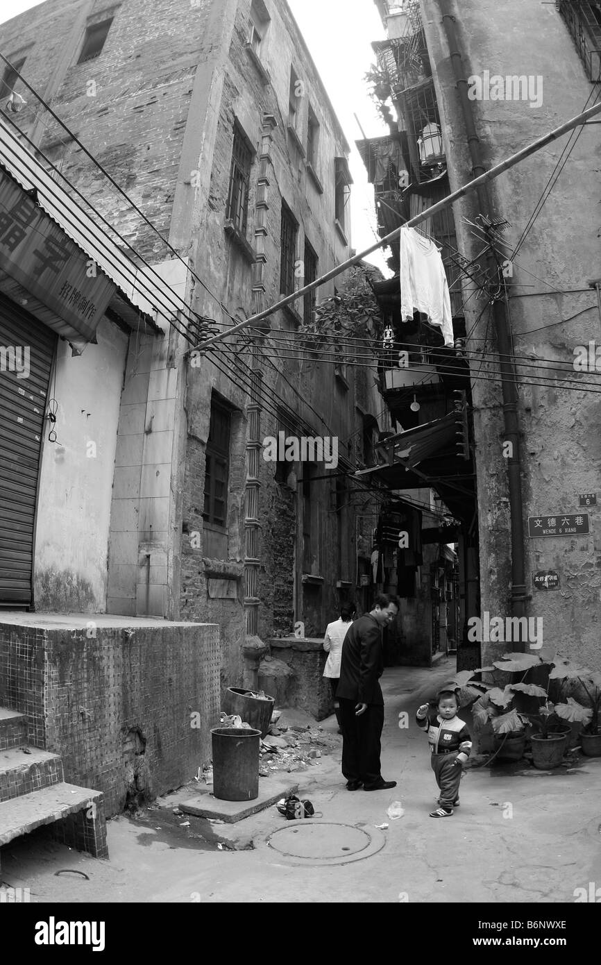 Bambino cinese e la famiglia all'interno della loro casa su una vecchia dimenticata strada laterale di Guangzhou un alto condannato edificio sorge maje Foto Stock