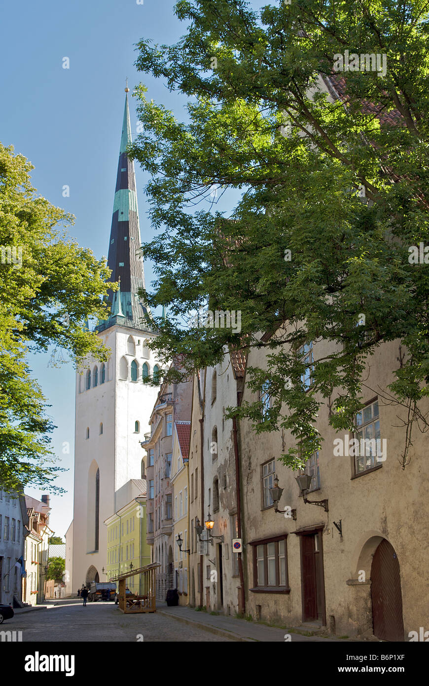Tranquilla strada alberata nel vecchio quartiere con St dell'Olaf nella Chiesa Vecchia di sfondo Tallinn Estonia Foto Stock