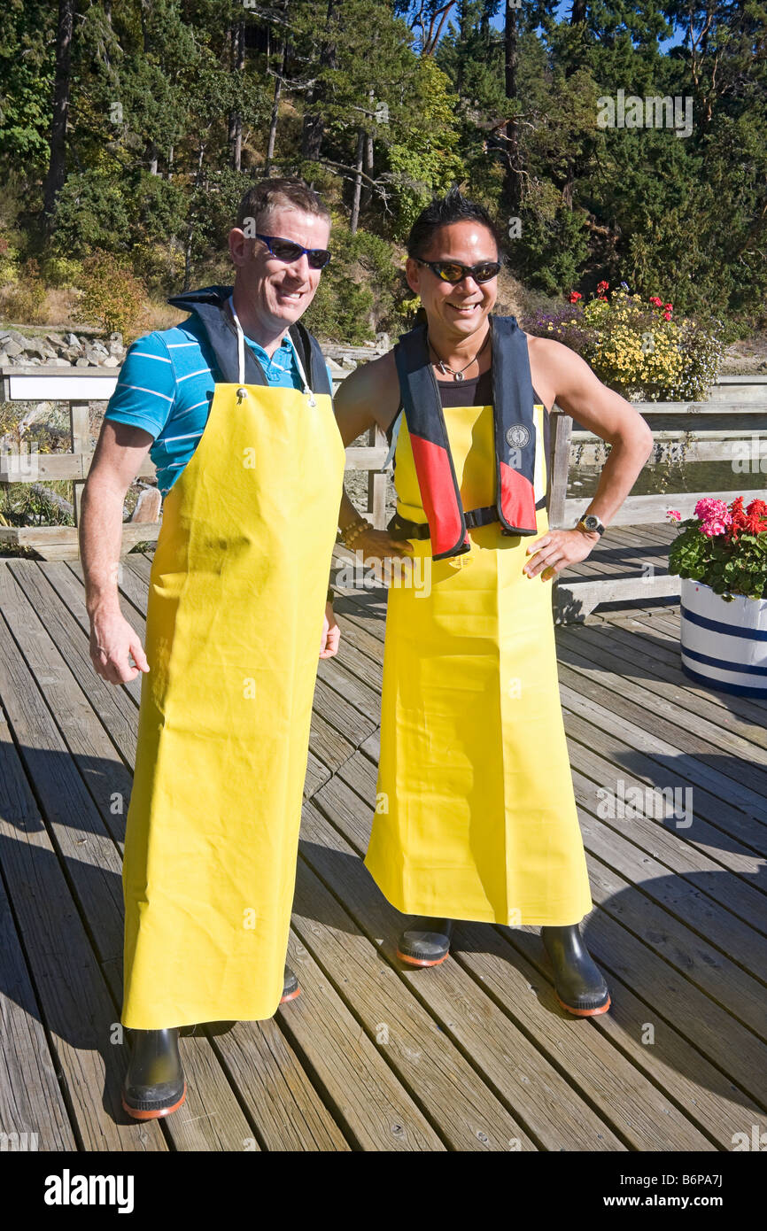 Due visitatori vestiti con grembiuli di gomma e gumboots prepararsi ad andare su un granchio barca di cattura in Salt Spring Island, Canada Foto Stock