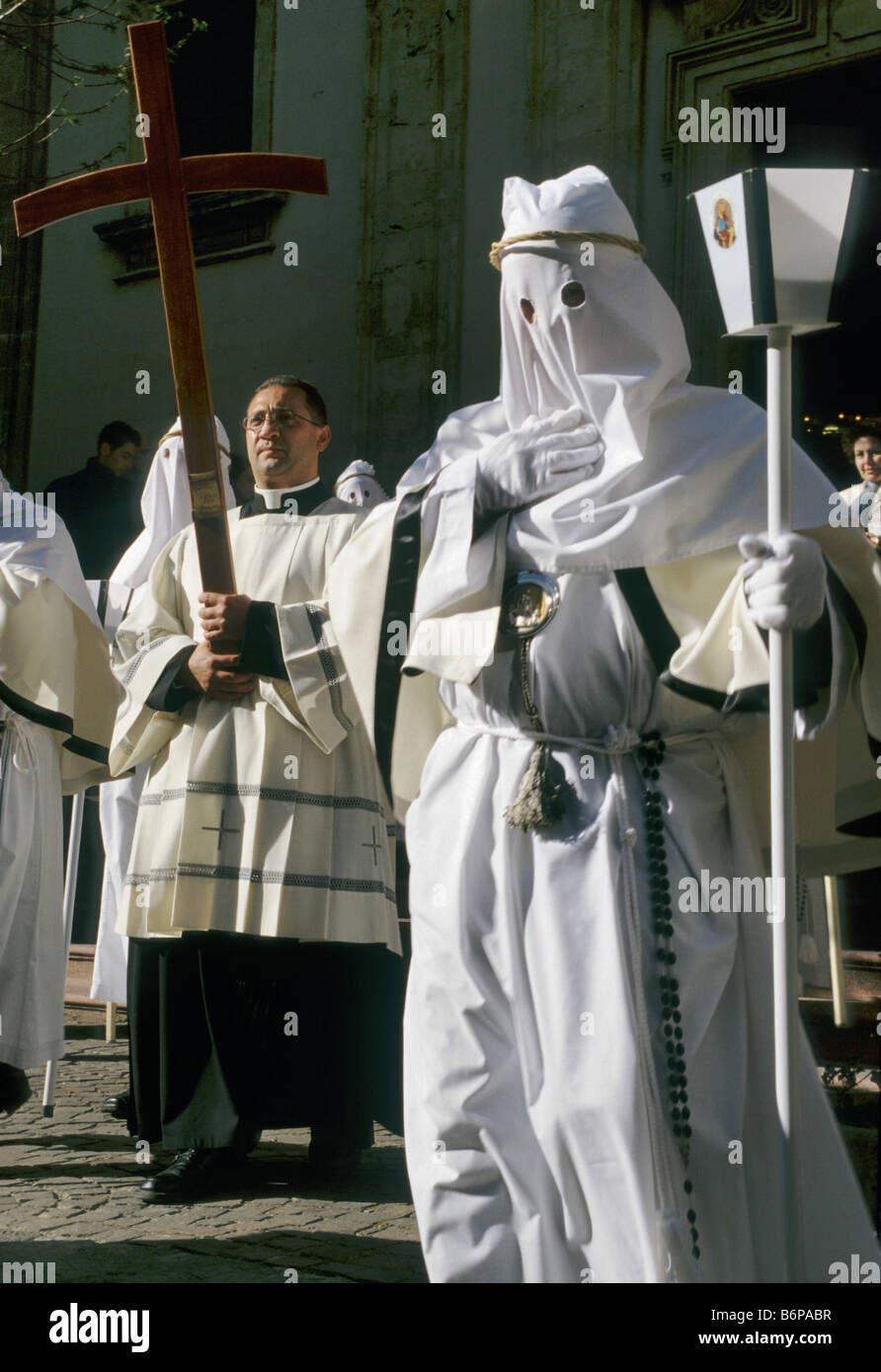 Il sacerdote e i penitenti a Settimana Santa Settimana Santa processione lasciando Cattedrale domenica delle Palme in Enna Sicilia Italia Foto Stock