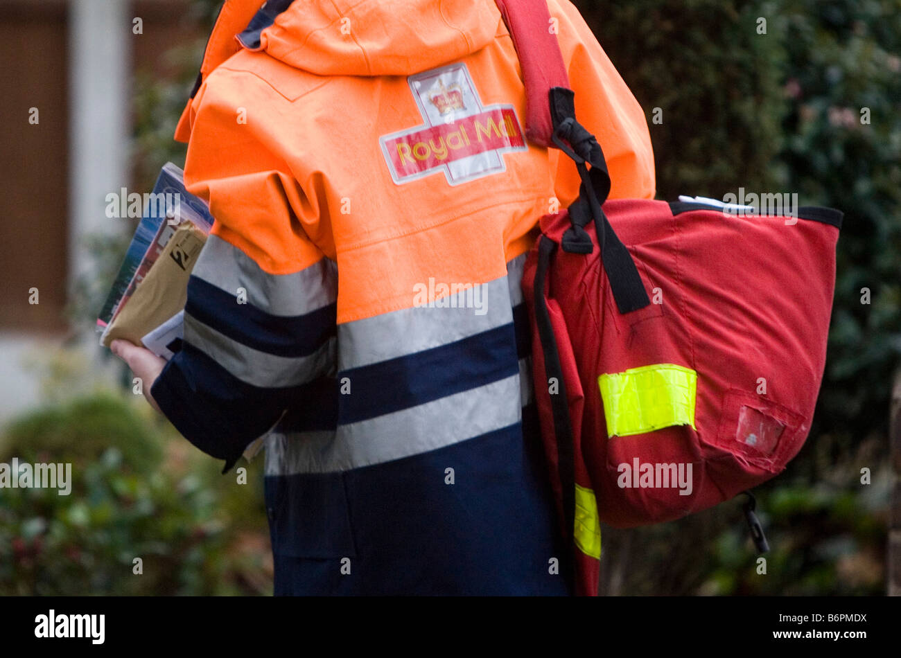 Un Royal Mail portalettere passeggiate sul suo turno consegnare le lettere in Essex U K Foto Stock