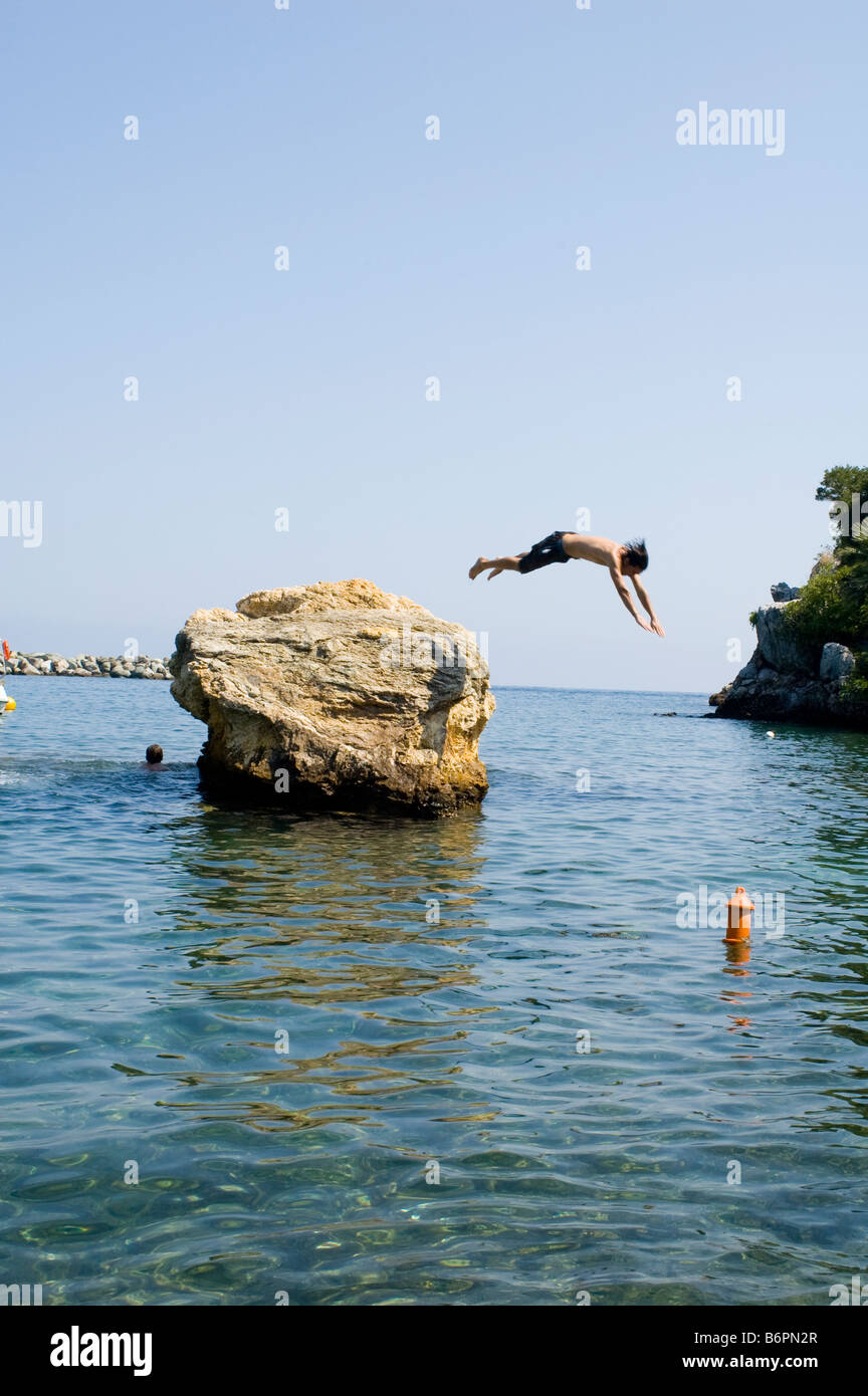 L'uomo diving off rock in Grecia Foto Stock