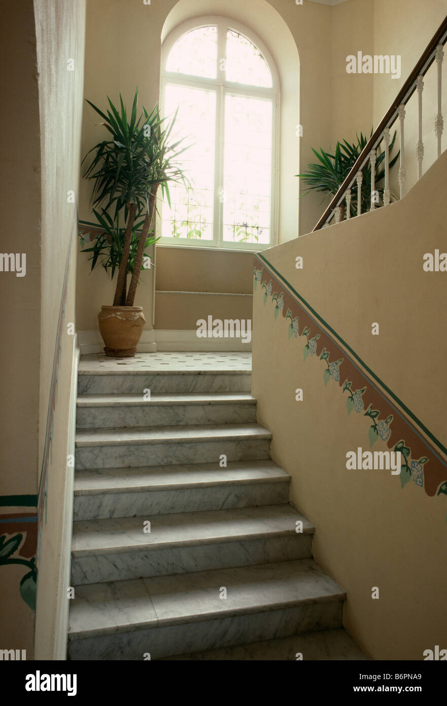 Confine dipinta sulla parete sopra le scale di pietra che conduce al piccolo approdo con finestra ad arco e houseplants Foto Stock