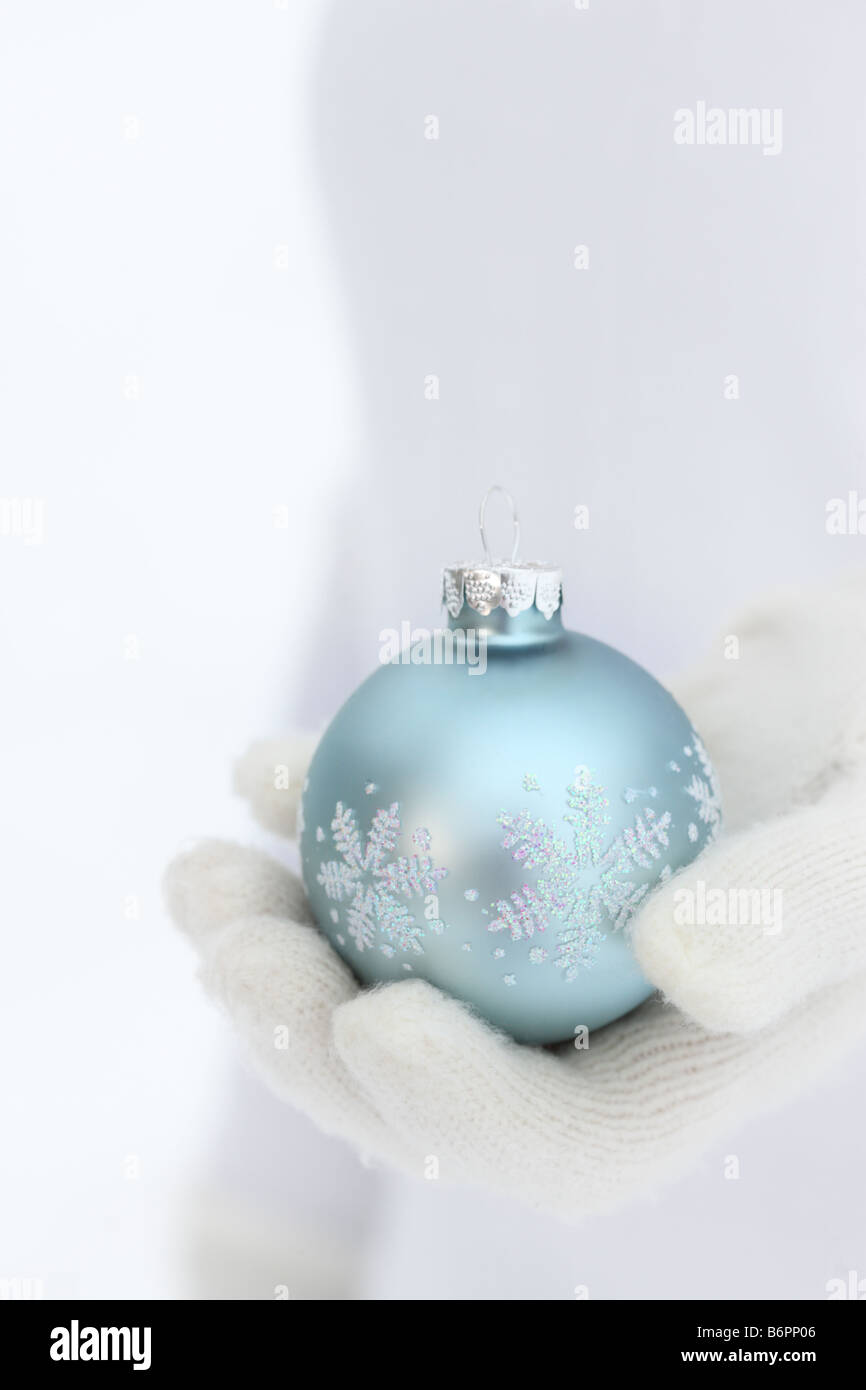 Le mani con guanti invernali blu holding il simbolo del fiocco di neve albero di Natale ornamento Foto Stock
