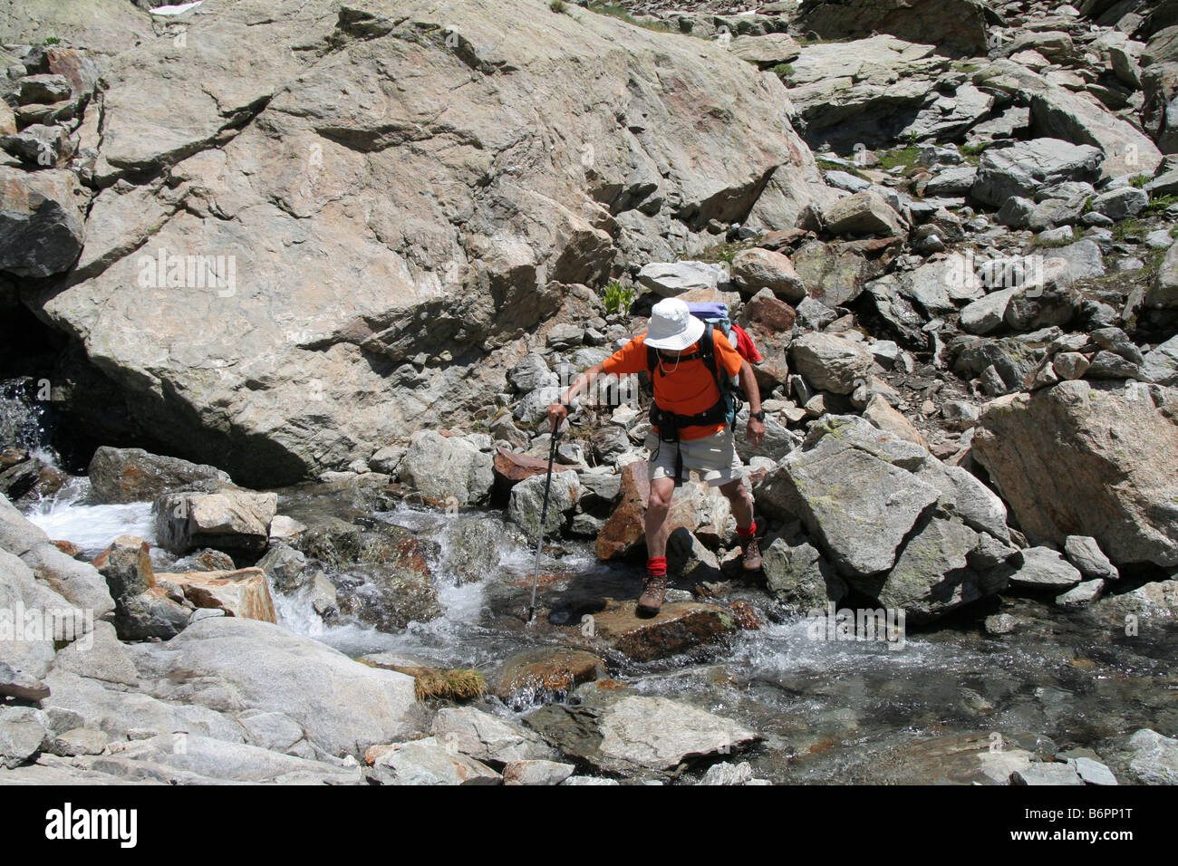 Walker attraversando un fragoroso torrente di montagna in francese Alpes Maritimes Foto Stock