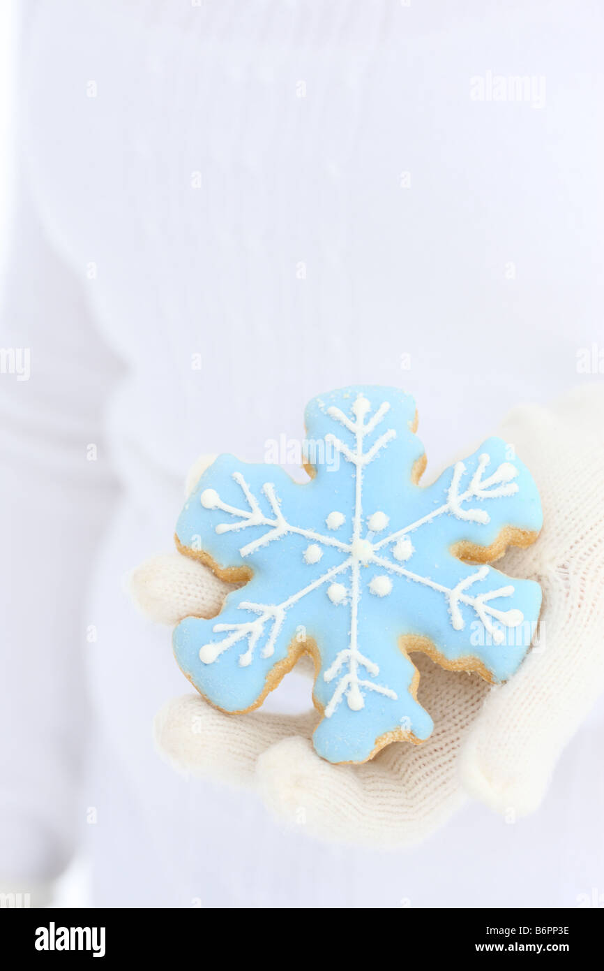 Le mani con guanti invernali tenendo premuto il simbolo del fiocco di neve cookie Foto Stock