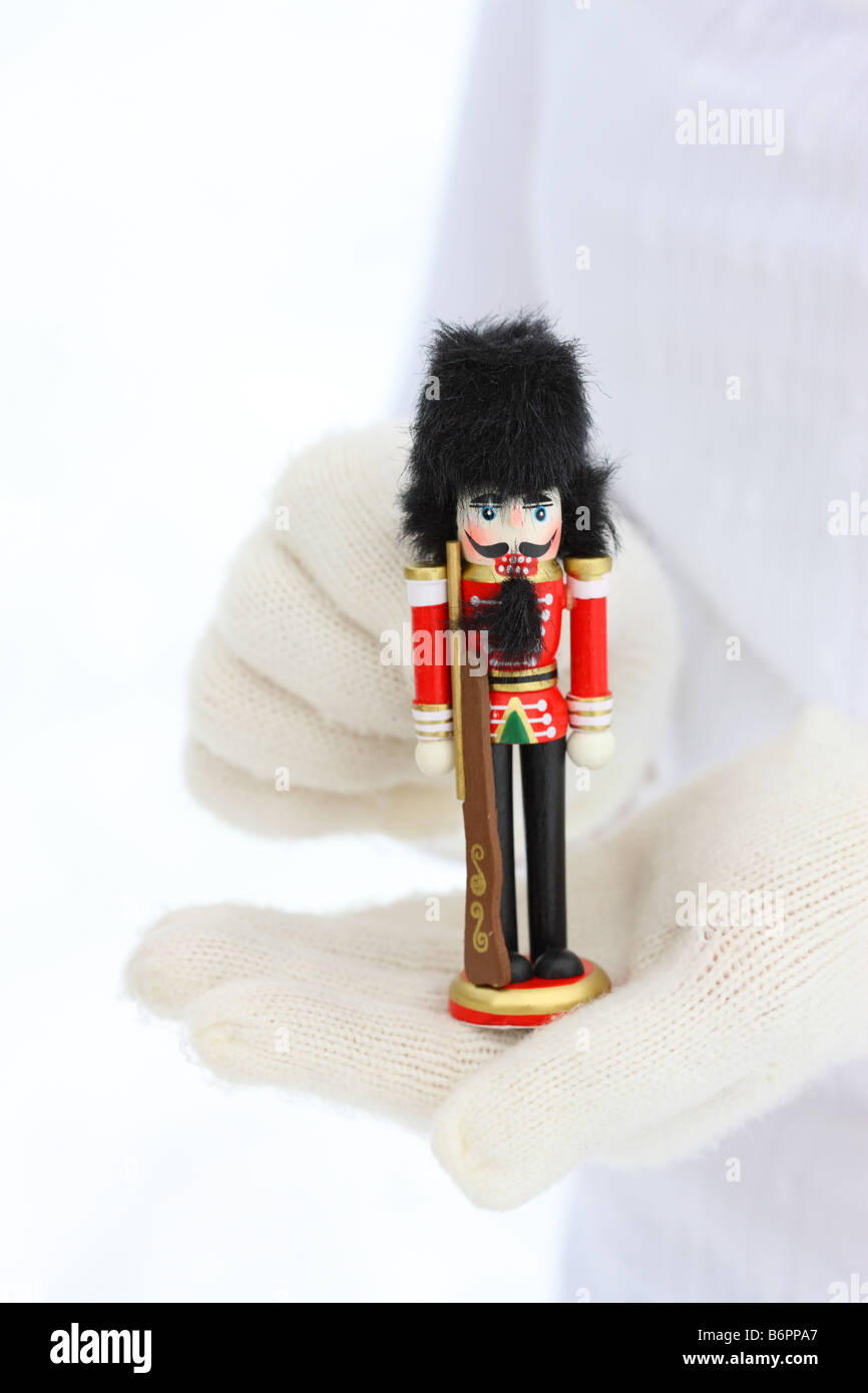 Le mani con guanti invernali tenendo il Natale Schiaccianoci Foto Stock