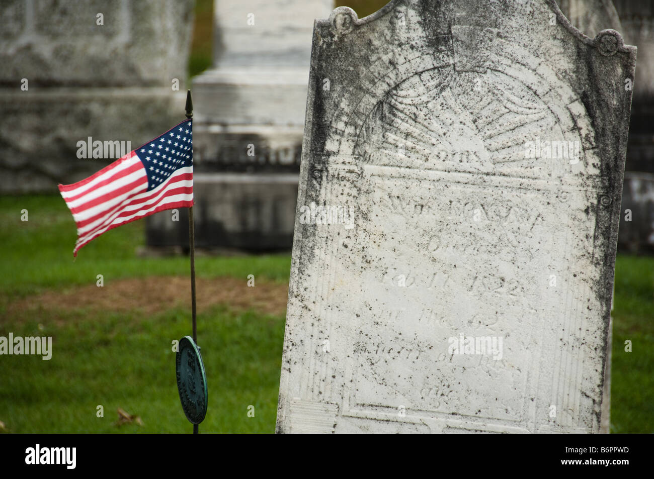 Noi bandiera accanto a una lapide in un cimitero vecchio Foto Stock