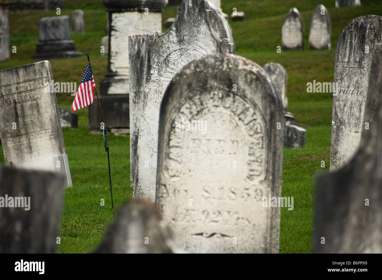 Noi bandiera accanto a una lapide in un cimitero vecchio Foto Stock