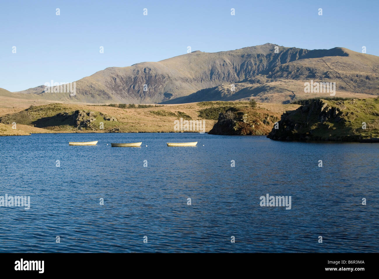Rhyd DDU Gwynedd North Wales dicembre guardando attraverso Llyn y dywarchen con tre pescherecci ormeggiati verso la catena montuosa Yr Wyddfa Snowdon Foto Stock