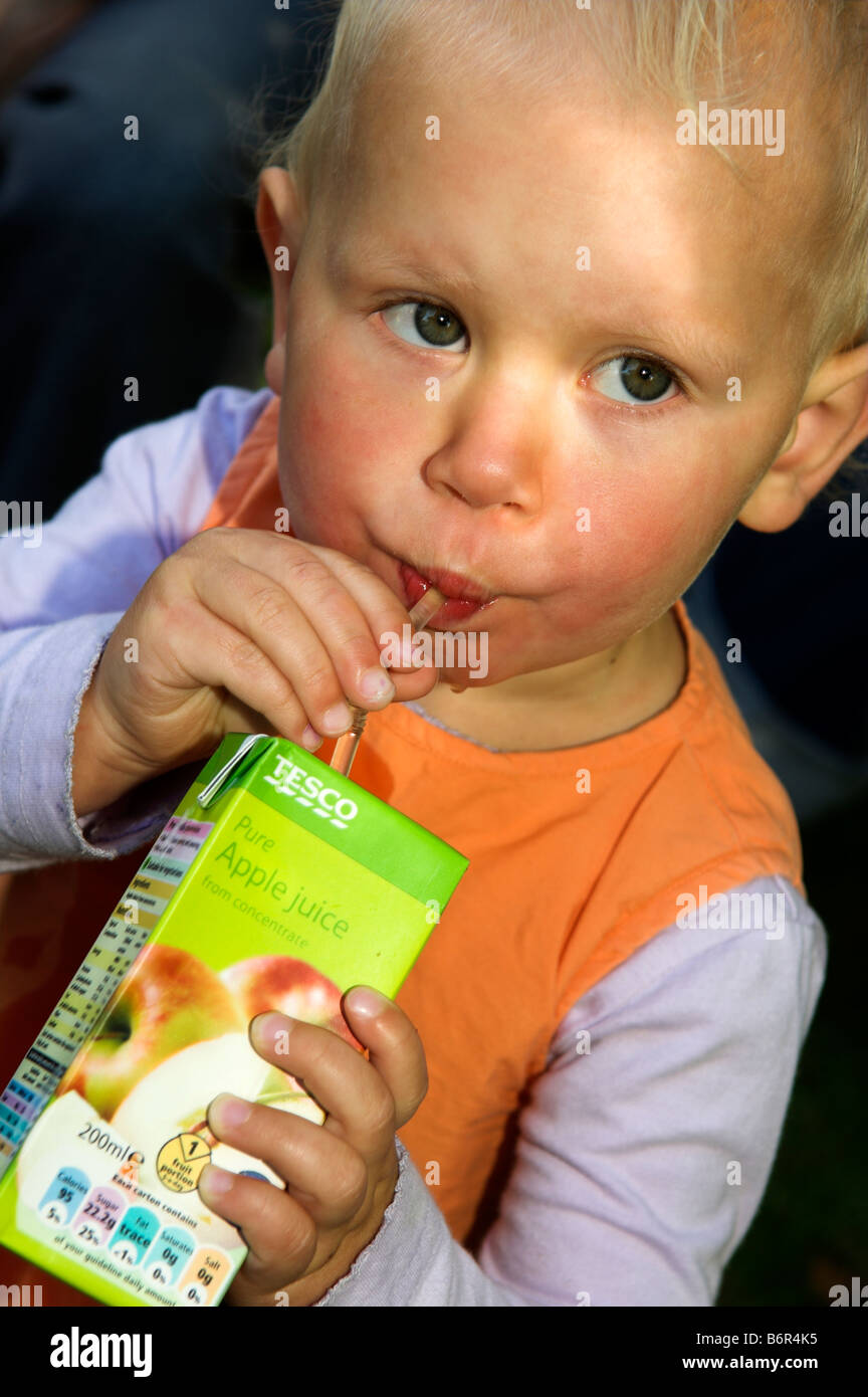 Tre anni di bambino beve dal cartone di succo Foto Stock