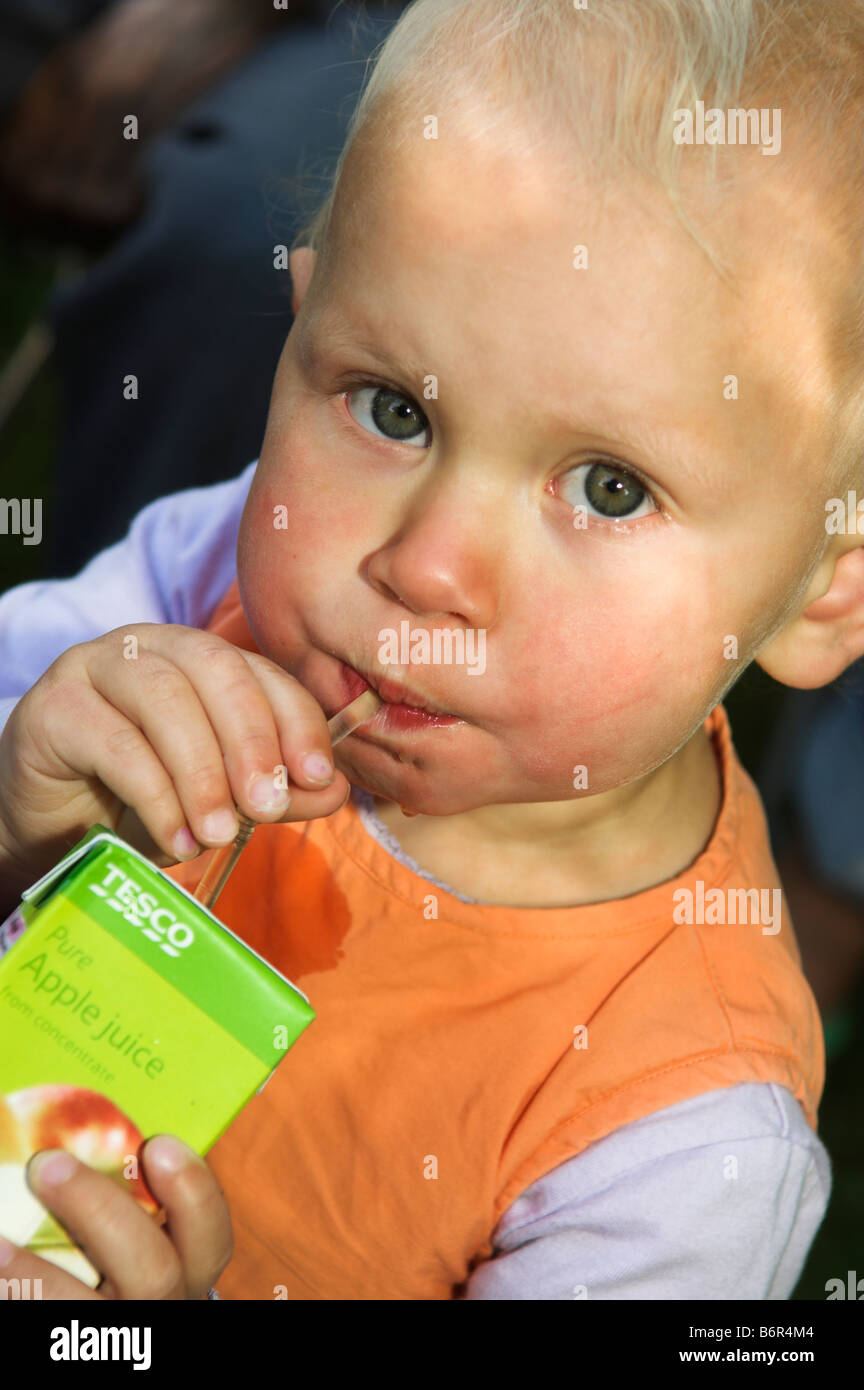 Tre anni di bambino beve dal cartone di succo Foto Stock