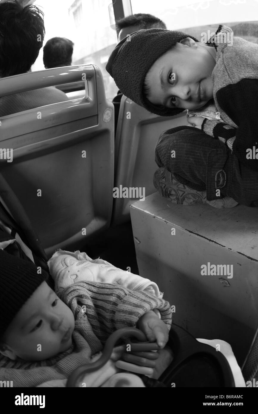Due fratelli sul servizio pubblico di autobus di città in Cina Guanjgzhou incrostazioni crisi economica mondiale violatign della Cina di un bambini Foto Stock